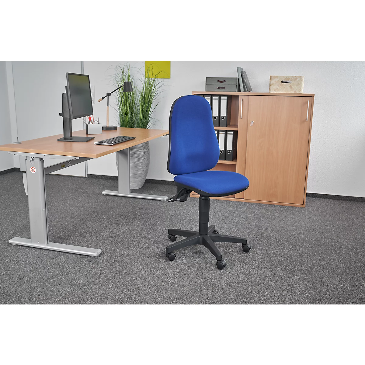 Office chair with a blue seat. To the right of it is a desk with a computer and cabinet.