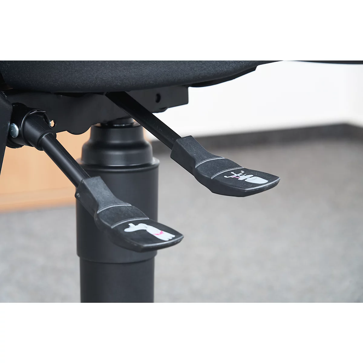 Close-up of the controls of an office chair. Two levers with pictograms.