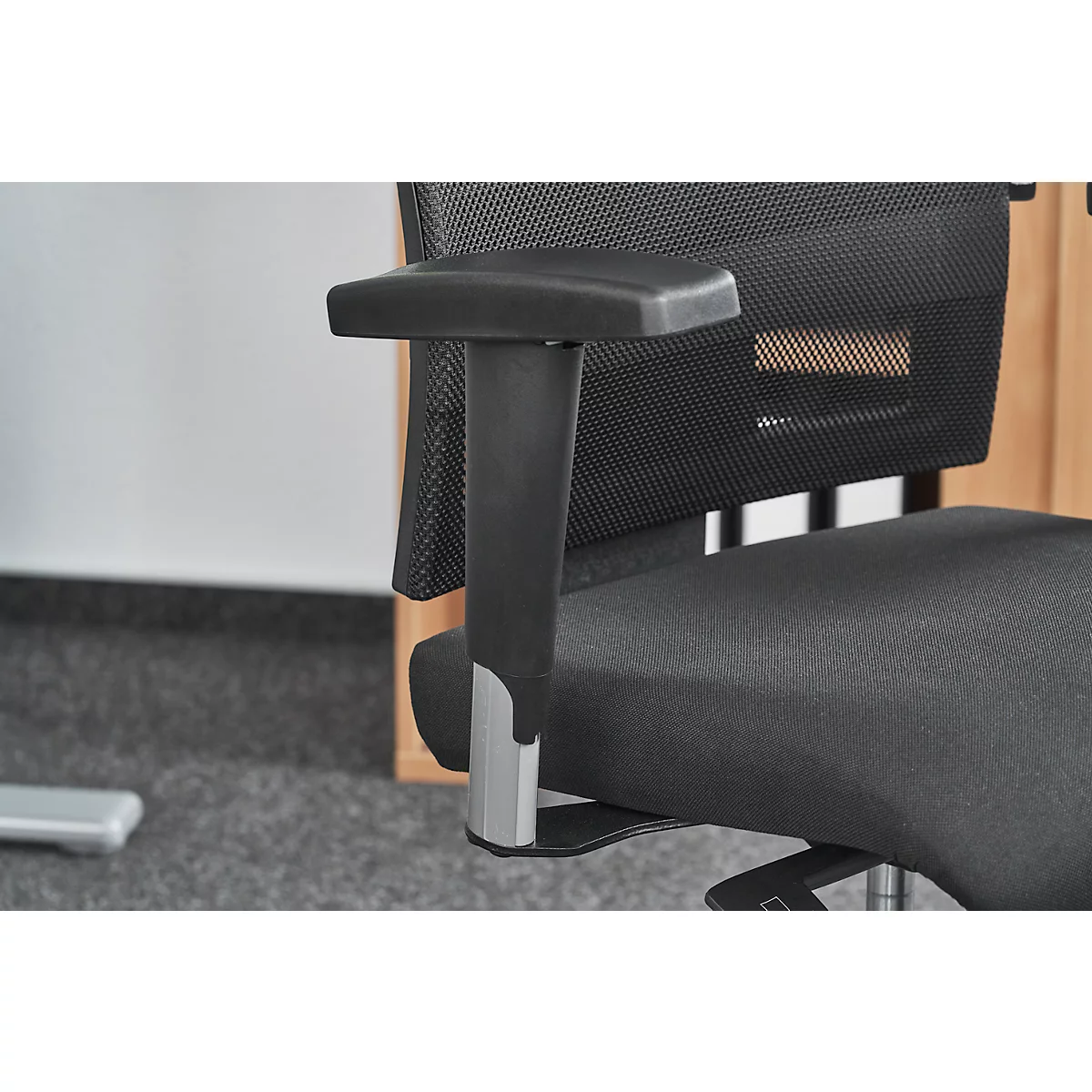 Close-up of a black office chair with armrest made of black plastic and silver metal.
