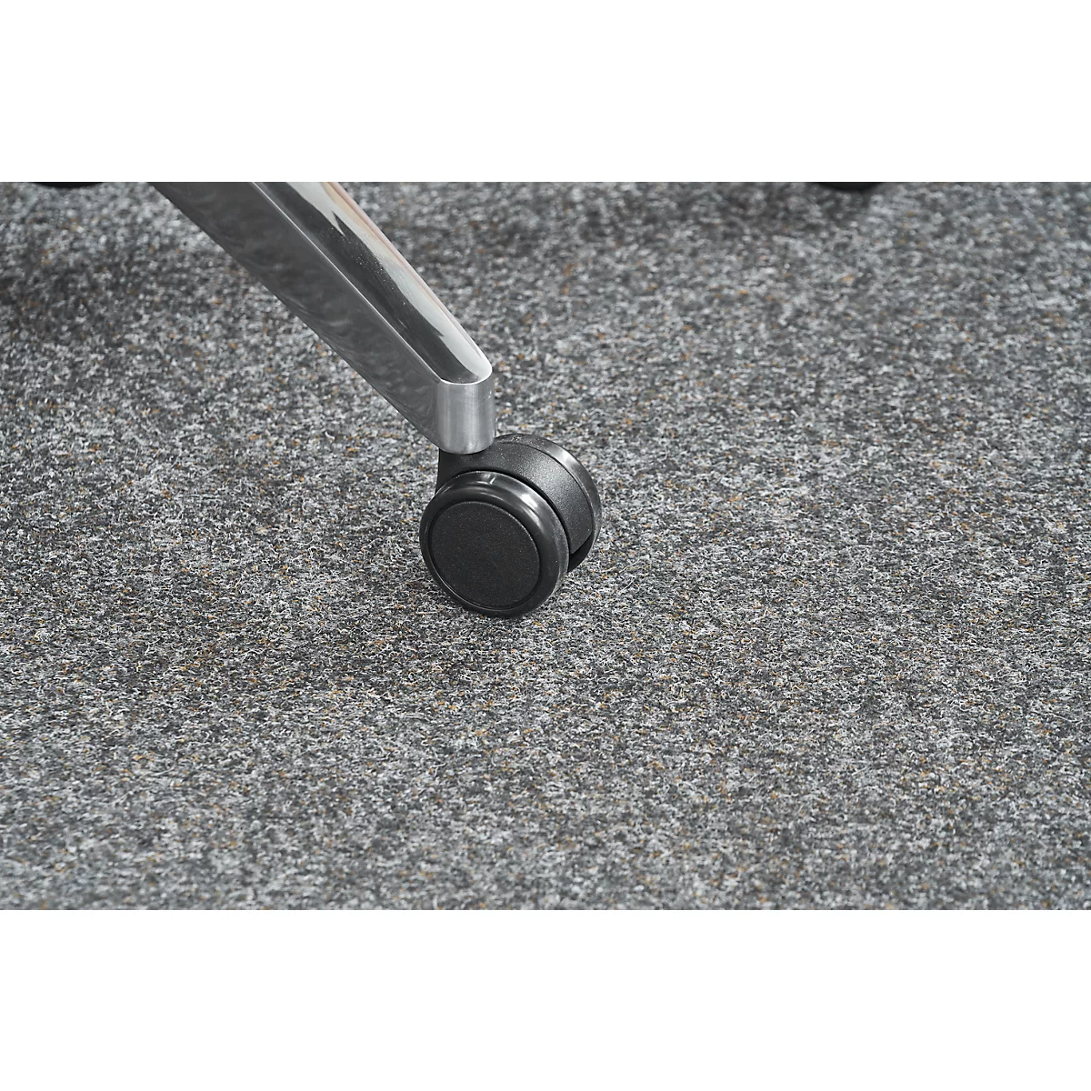 Close-up of chair leg with wheel on gray carpeted floor.