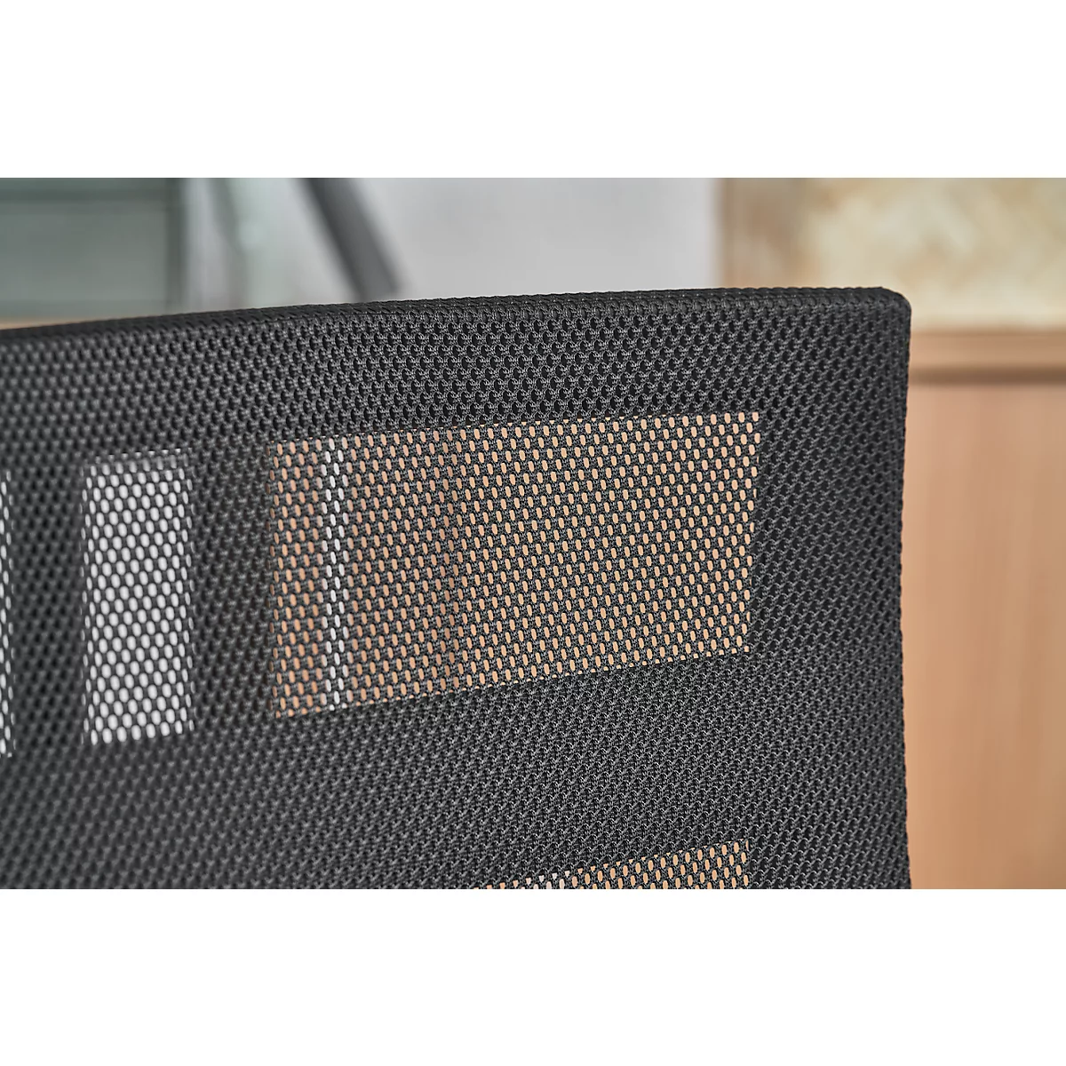 Close-up of a chair back with black mesh fabric and rectangular, light brown areas.