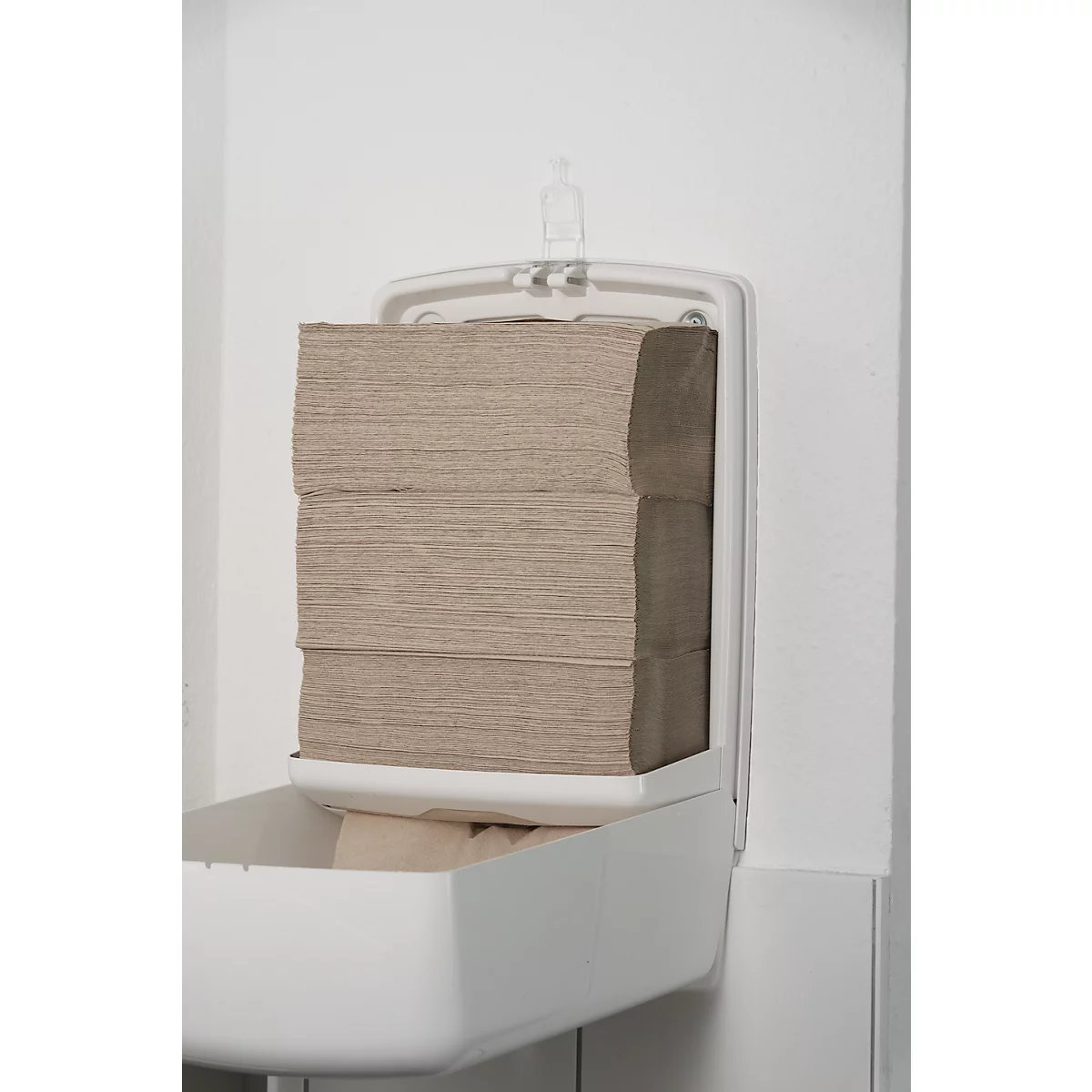 A white paper towel dispenser on a white wall. The towels are beige and stacked.