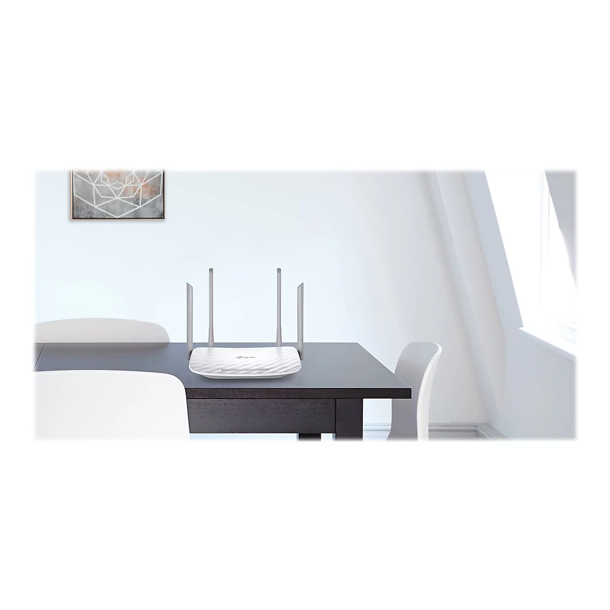 Ein weiÃŸer Router mit vier Antennen steht auf einem dunklen Tisch. Im Hintergrund: StÃ¼hle, ein Bild und ein Fenster.