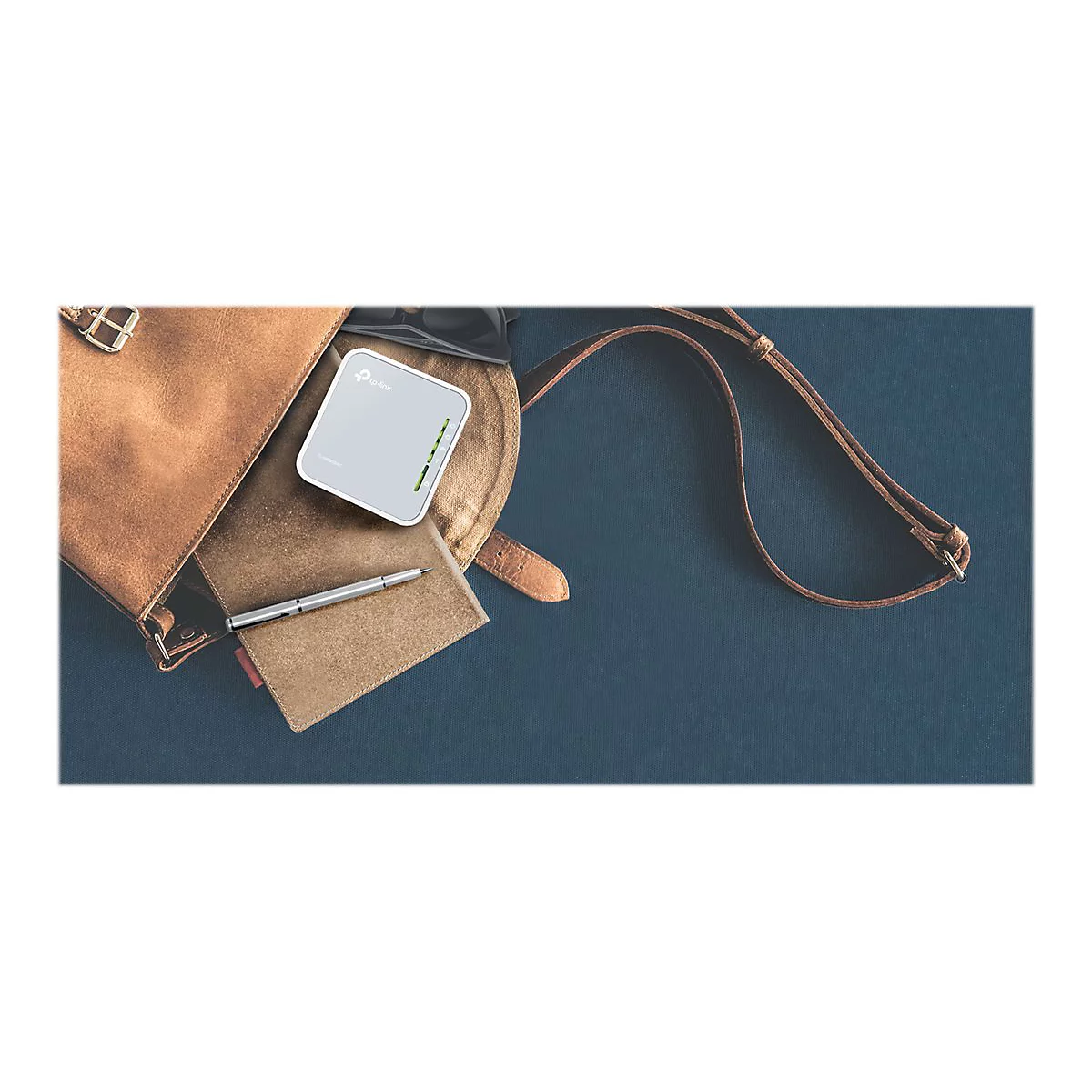Graues WLAN-GerÃ¤t mit brauner Ledertasche, Notizbuch und Stift auf blauem Hintergrund.