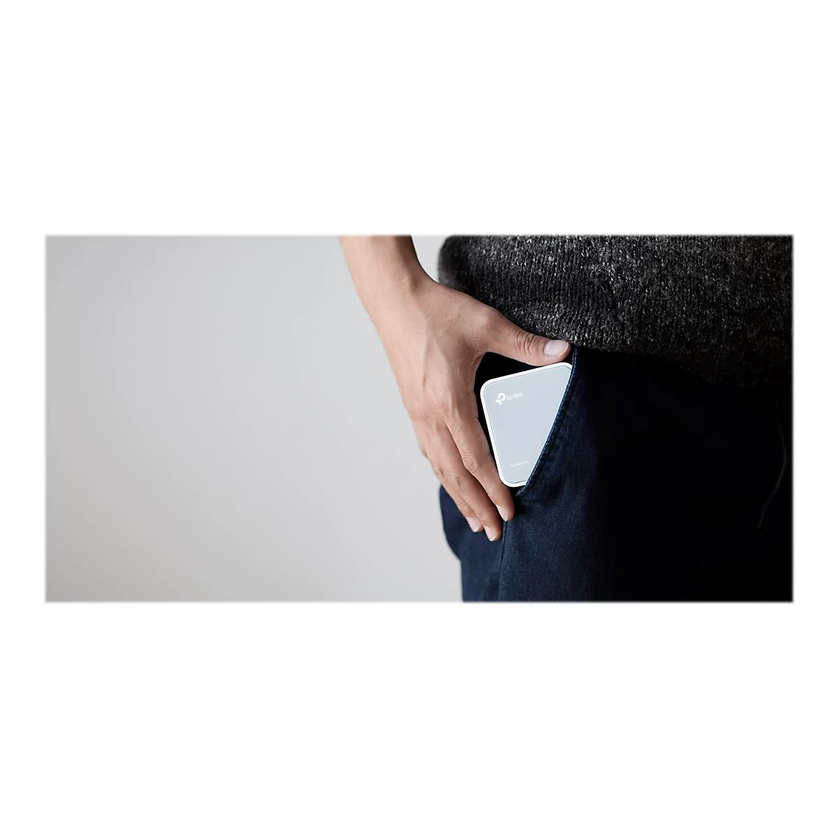 Ein Smartphone-Ã¤hnliches GerÃ¤t in der Hosentasche. Helle Farbe mit abgerundeten Ecken, sichtbar ist eine Hand, Teil eines Pullovers und die Jeans.