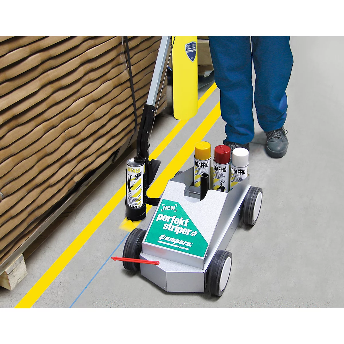 Une personne utilise une machine de marquage routier pour tracer un trait jaune au sol. En arrière-plan, on peut voir une étagère et des bombes de peinture.