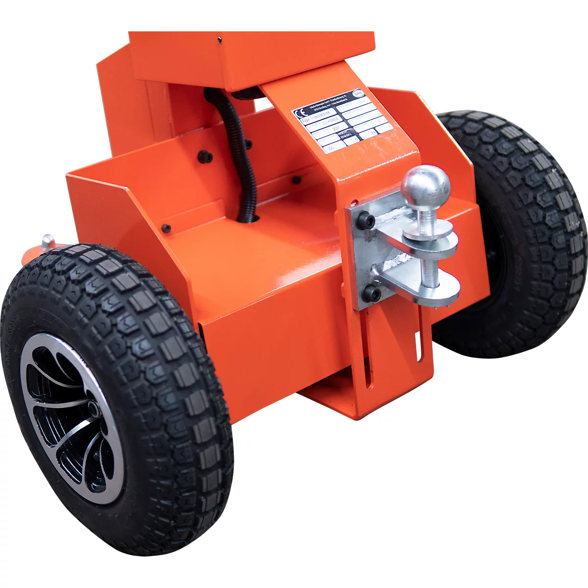 Gros plan d'un appareil orange avec deux roues, une attache de remorque et une plaque signalétique.