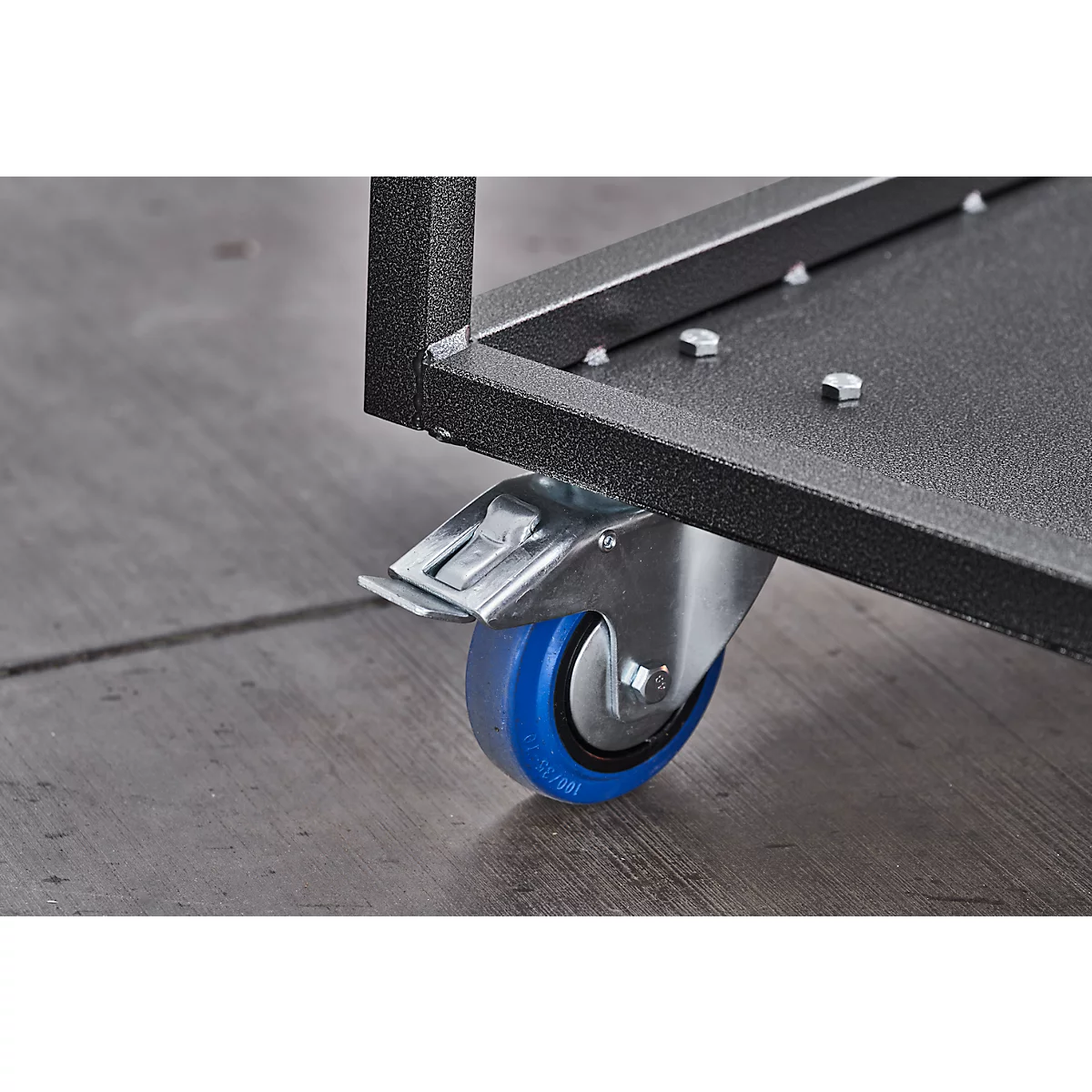 Close-up of a black metal frame with a wheel with a blue tread attached. The floor is grey.