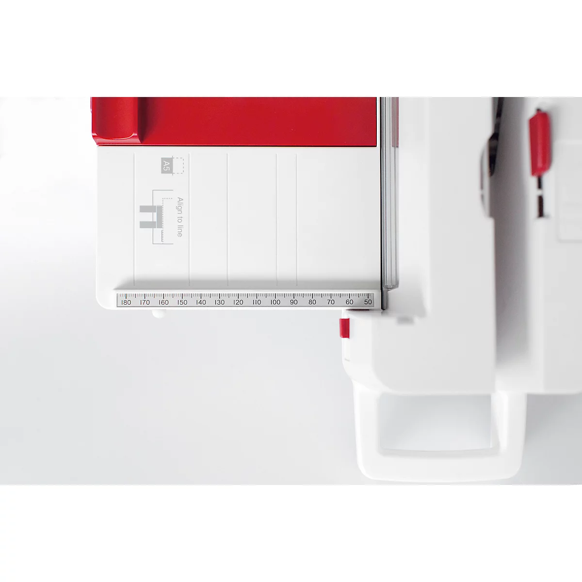 Detail shot of a white paper cutter with red accent. A ruler in cm is visible.