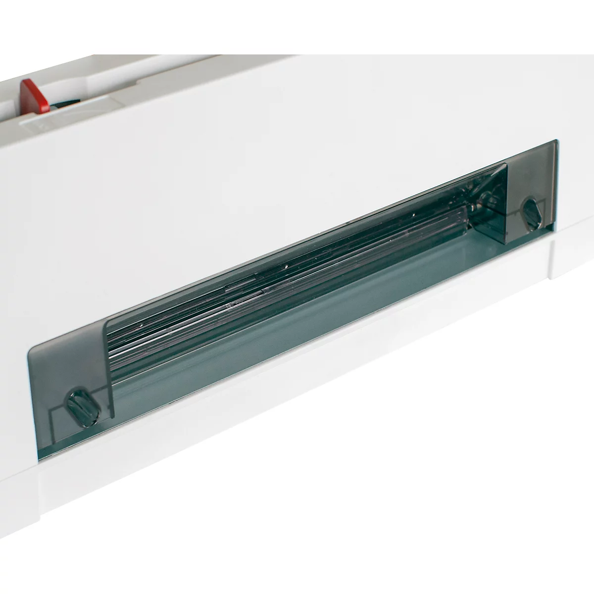 Close-up of a white machine featuring a transparent, elongated window. The machine has a red button and screws.