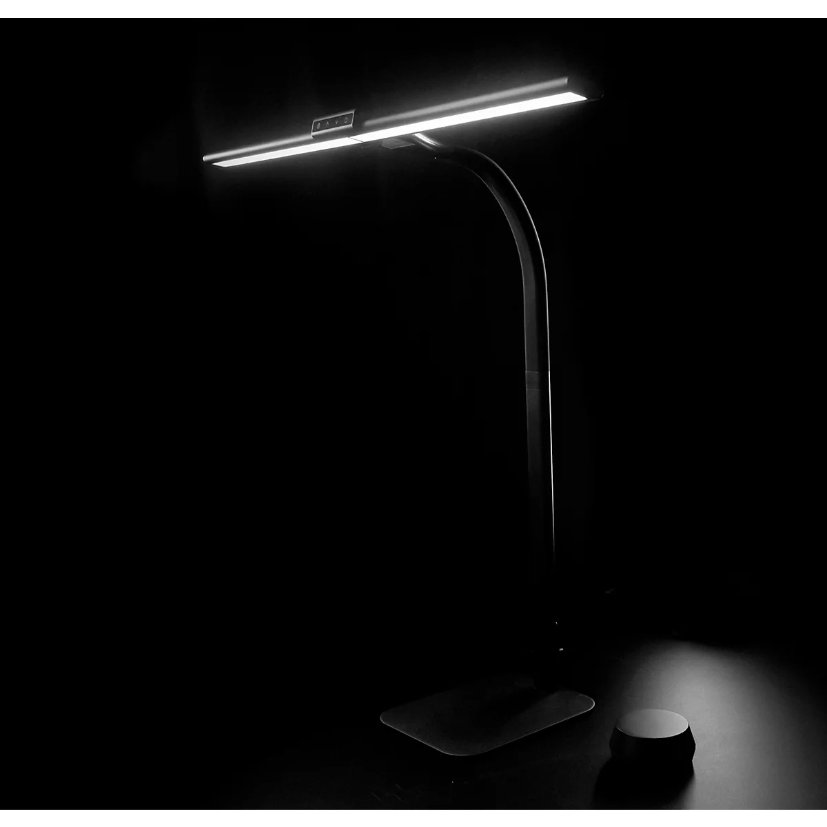 Lampe de bureau avec une lumière vive, éclairant une pièce sombre.