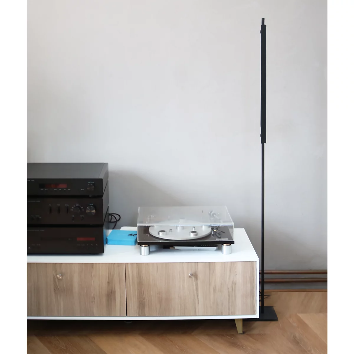 Ein Plattenspieler und Stereo-Komponenten stehen auf einem Sideboard neben einer hohen, schwarzen Stehlampe.