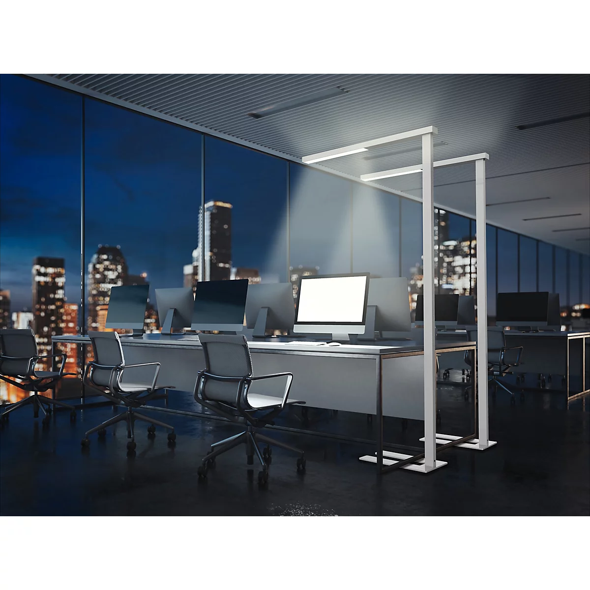 Moderne Büro-Stehleuchte erhellt einen Arbeitsplatz in einem nächtlichen Büro mit Blick auf die Skyline.