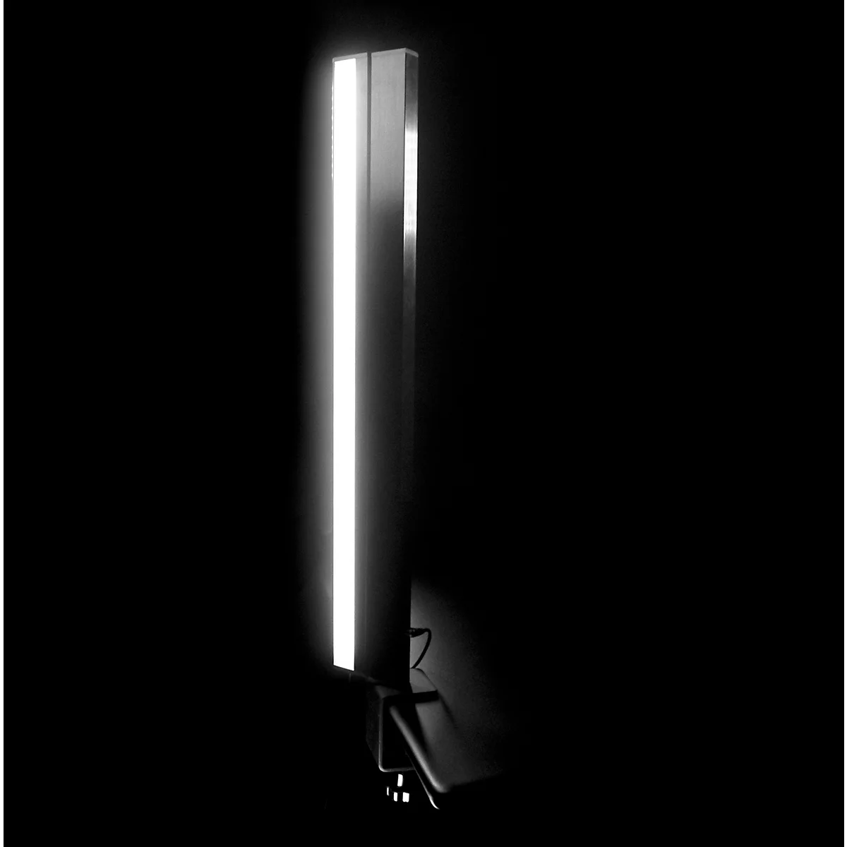 Vertical lamp, silver-colored, with bright light strip in a dark environment.