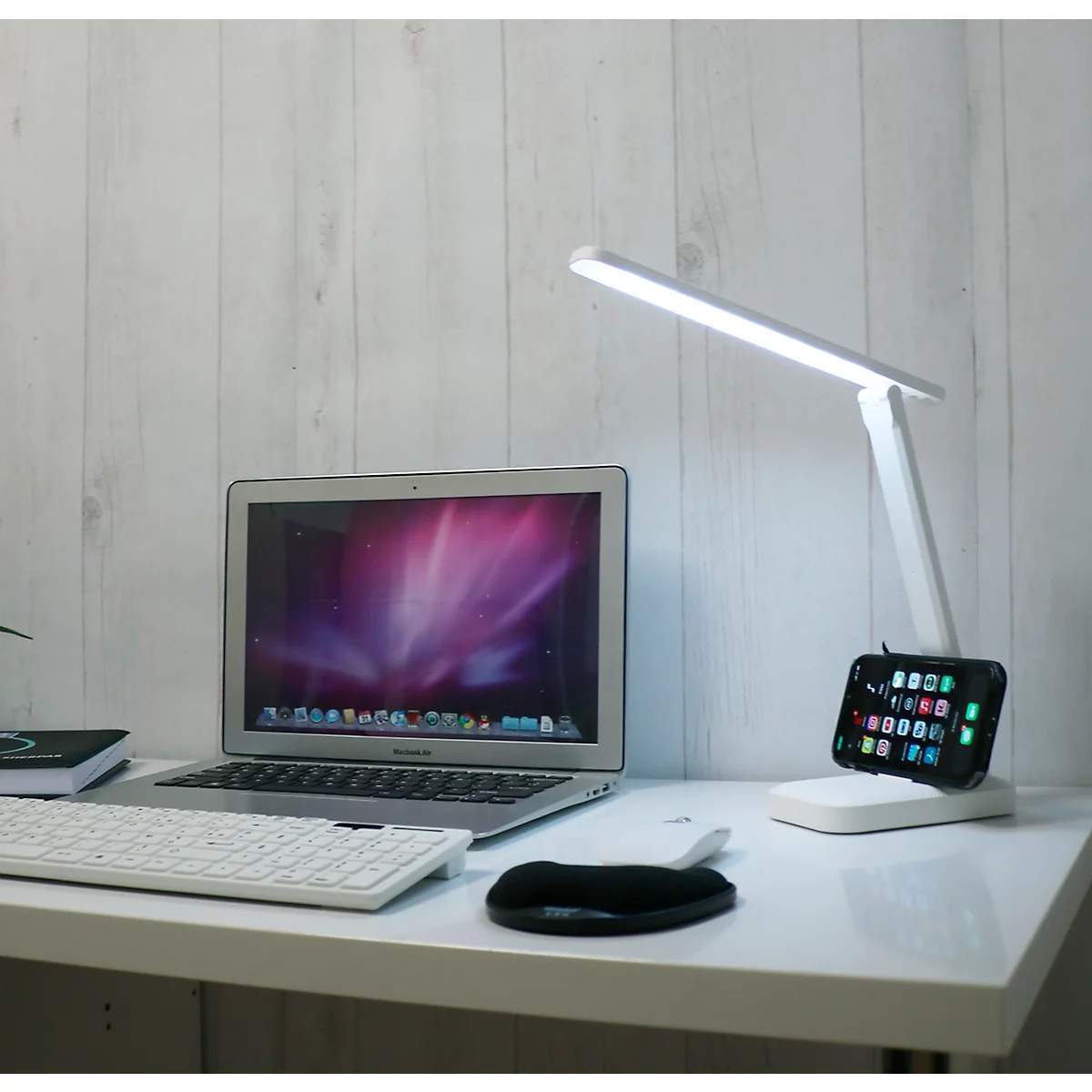 Witte bureau met laptop, toetsenbord, muis, lamp en smartphone met apps.