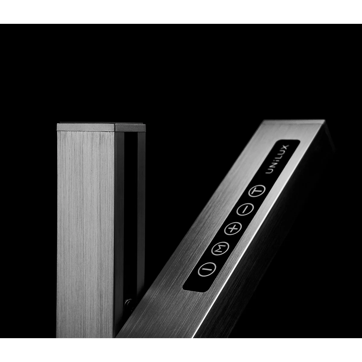 Close-up van een lamp met zilverkleurige behuizing, bedieningselementen en het opschrift UNILUX. Zwarte achtergrond.