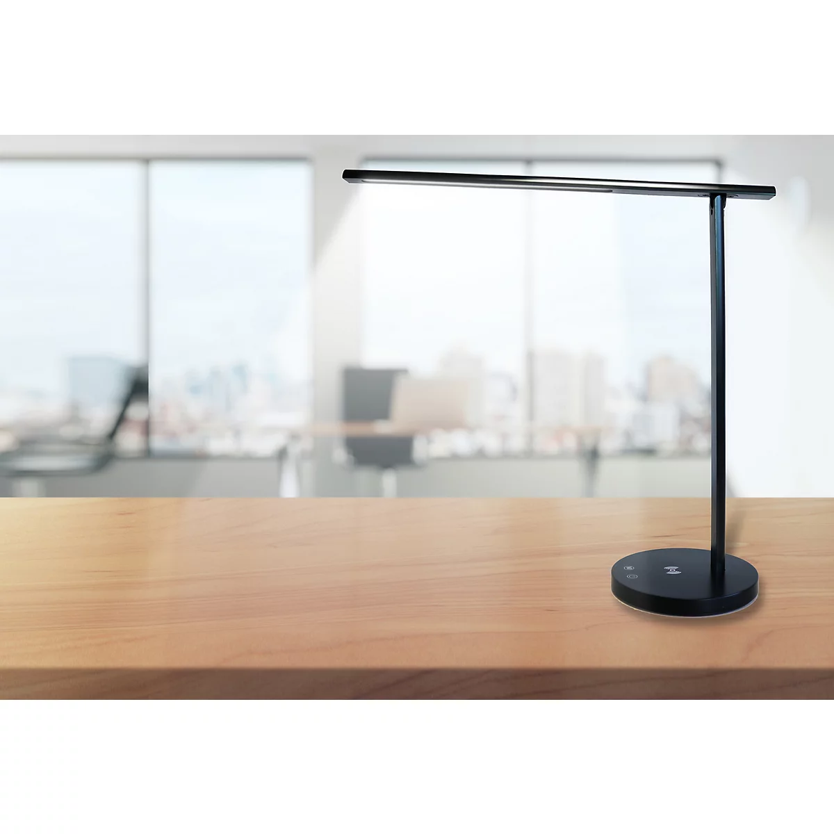 Schlanke, schwarze LED-Schreibtischlampe auf einer hellen Holzoberfläche vor unscharfem Büro-Hintergrund.