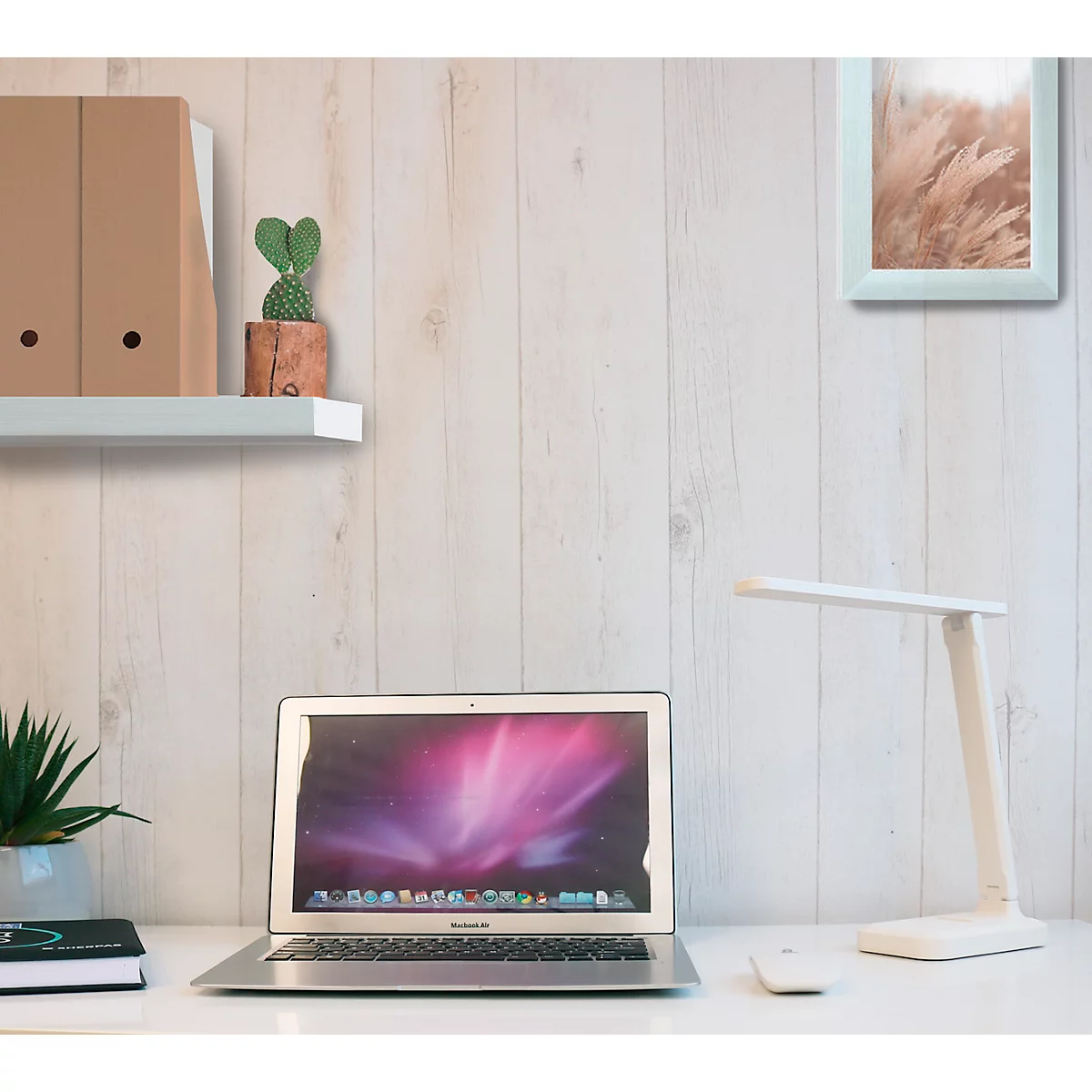 Ein Arbeitsplatz mit Laptop, Lampe und Pflanzen vor einer Holzverkleidung.