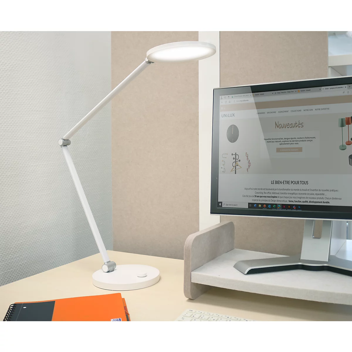 Weiße LED-Schreibtischlampe leuchtet auf einem aufgeräumten Büroschreibtisch neben einem Computerbildschirm.