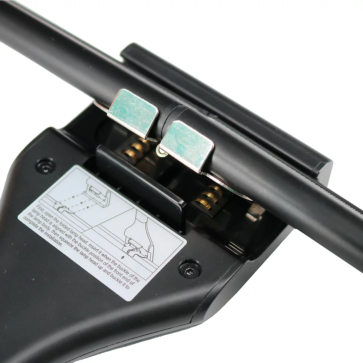 Close-up: Zwart apparaat met metalen clips, instructielabel en een zwarte buis.