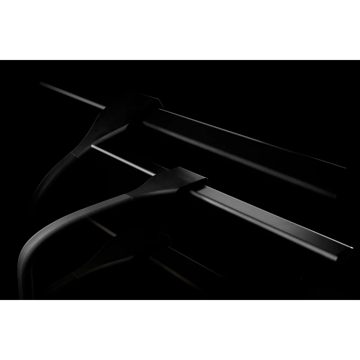 Close-up van twee zwarte kleerhangers op een zwarte achtergrond, lichte schaduwen.