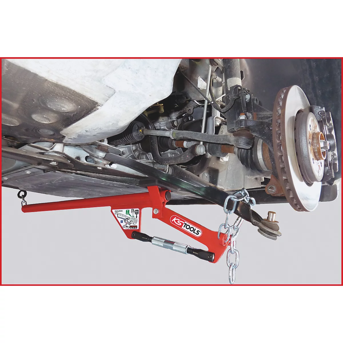 Rotes Werkzeug zum Ausdrücken von Kugelgelenken an einem Autoreifen.