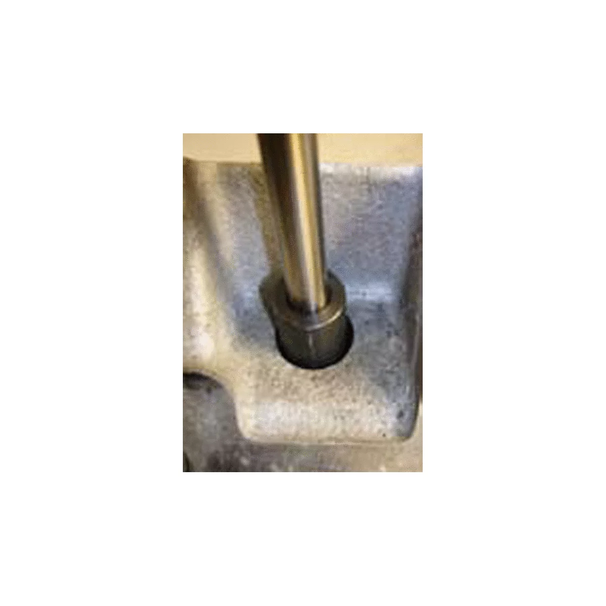 Stahlstange in einer Bohrung mit Metallfassung. Die Stange ist senkrecht. Detailaufnahme.