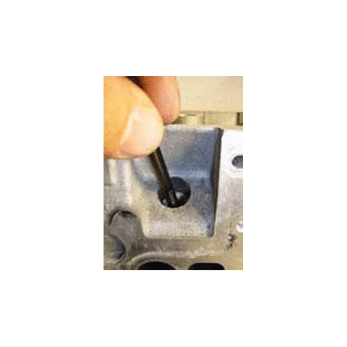 Ein Finger führt einen schwarzen Stab in ein Loch in einem grauen Metallteil.