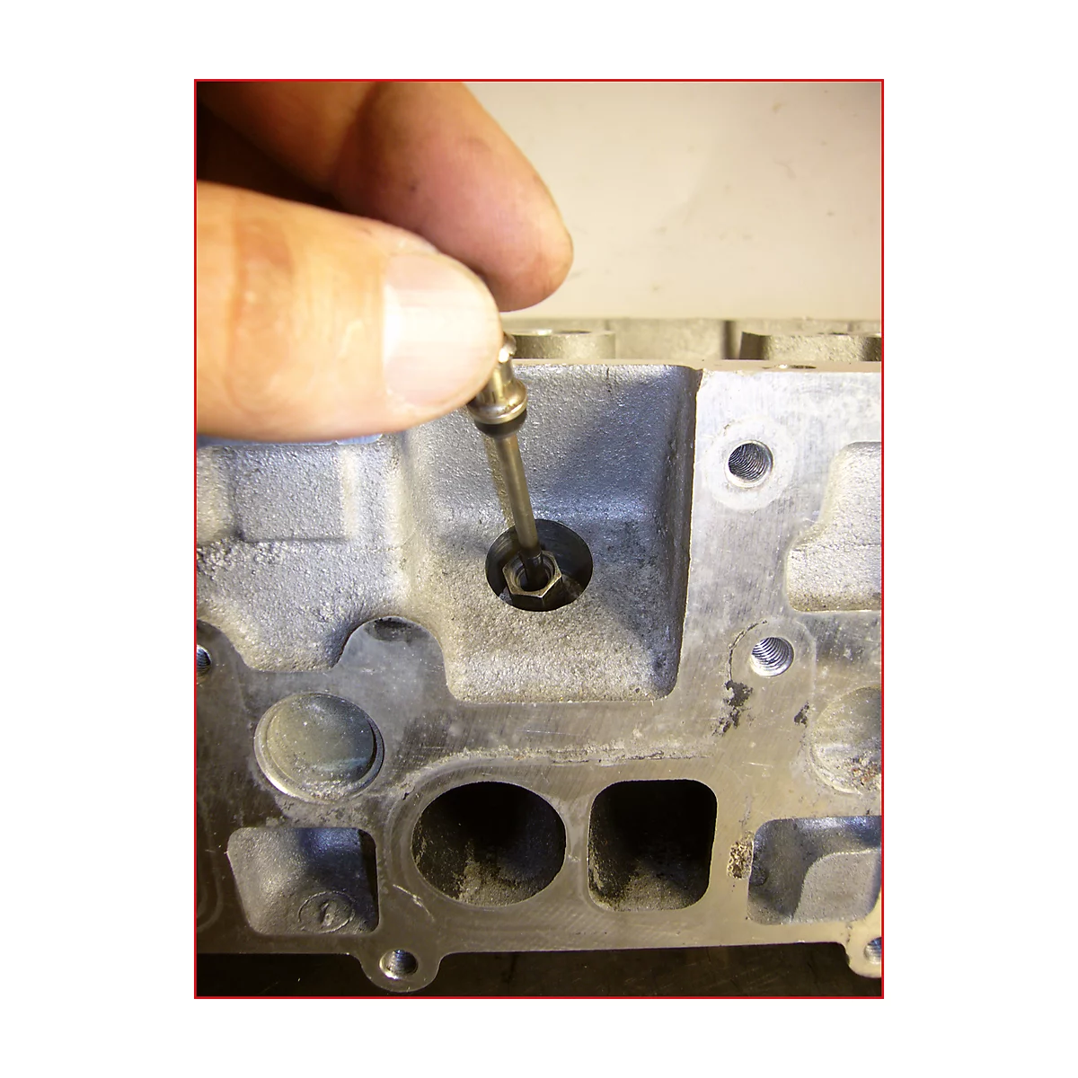 Hand hält Werkzeug in Zylinderkopf. Detailaufnahme zur Reparatur oder Wartung.