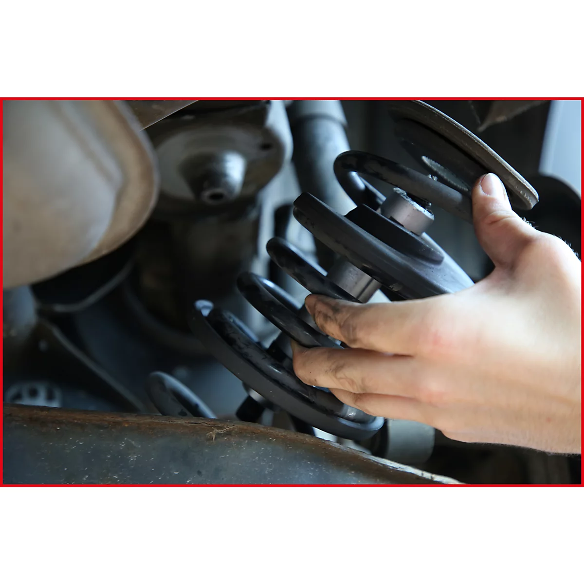 Hand hält einen Stoßdämpfer in einem Auto.