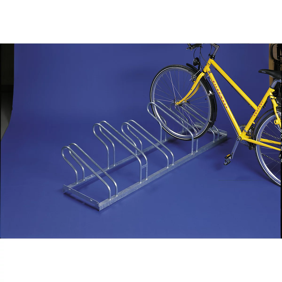 Metal bike rack with a yellow bike in it. On a blue background.