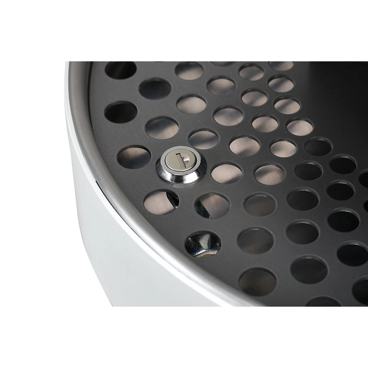 Detailopname van een rond, geperforeerd oppervlak met een rond slot en een witte, afgeronde rand.