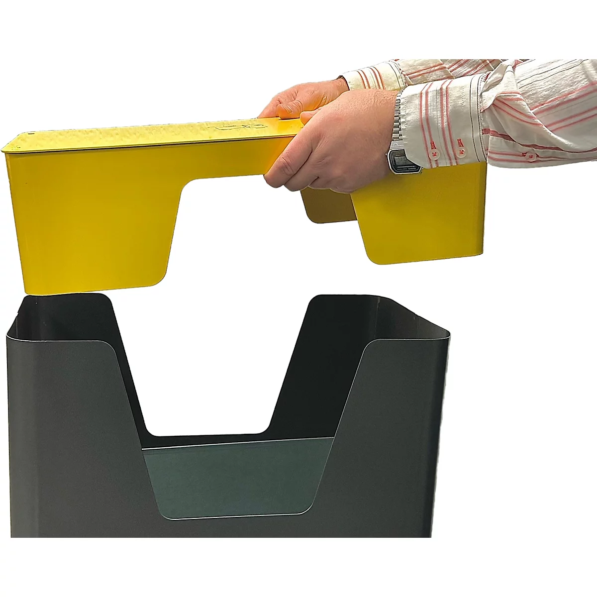 Handen houden een gele inzetstuk boven een zwarte container. De vormen passen in elkaar.