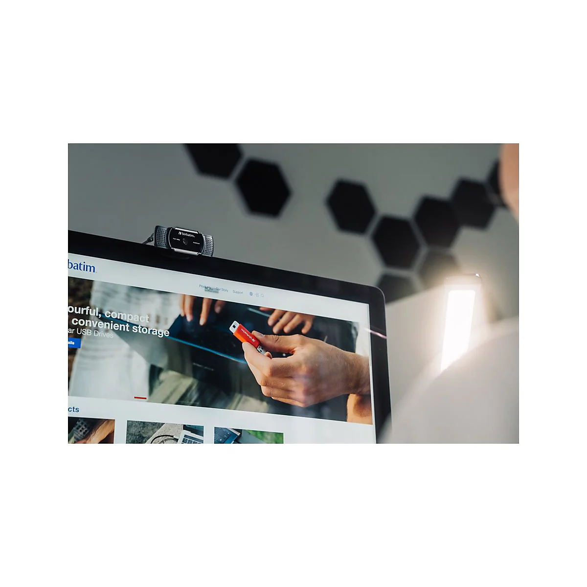 Ein Laptop mit einer Webcam, auf dem ein Mann einen roten USB-Stick auf einer Website betrachtet.
