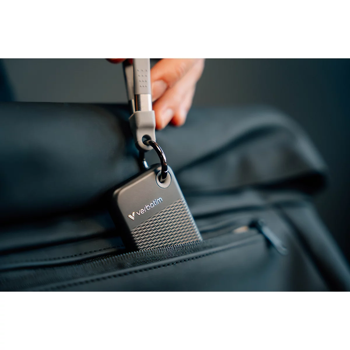 Ein schwarzer Verbatim-Tracker an einer Handtasche befestigt.