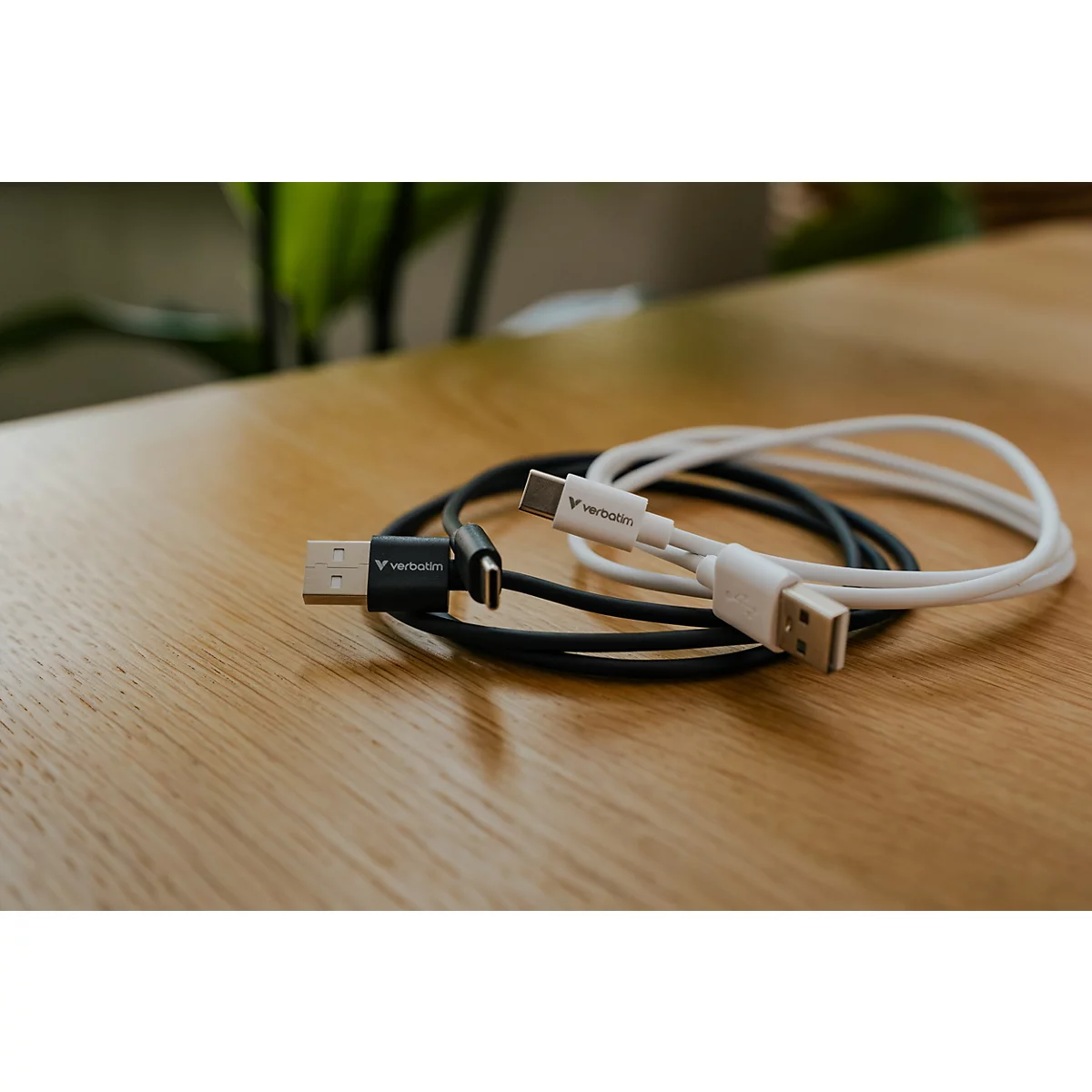 Ein schwarzes und ein weißes USB-C-Kabel liegen auf einem Holztisch.