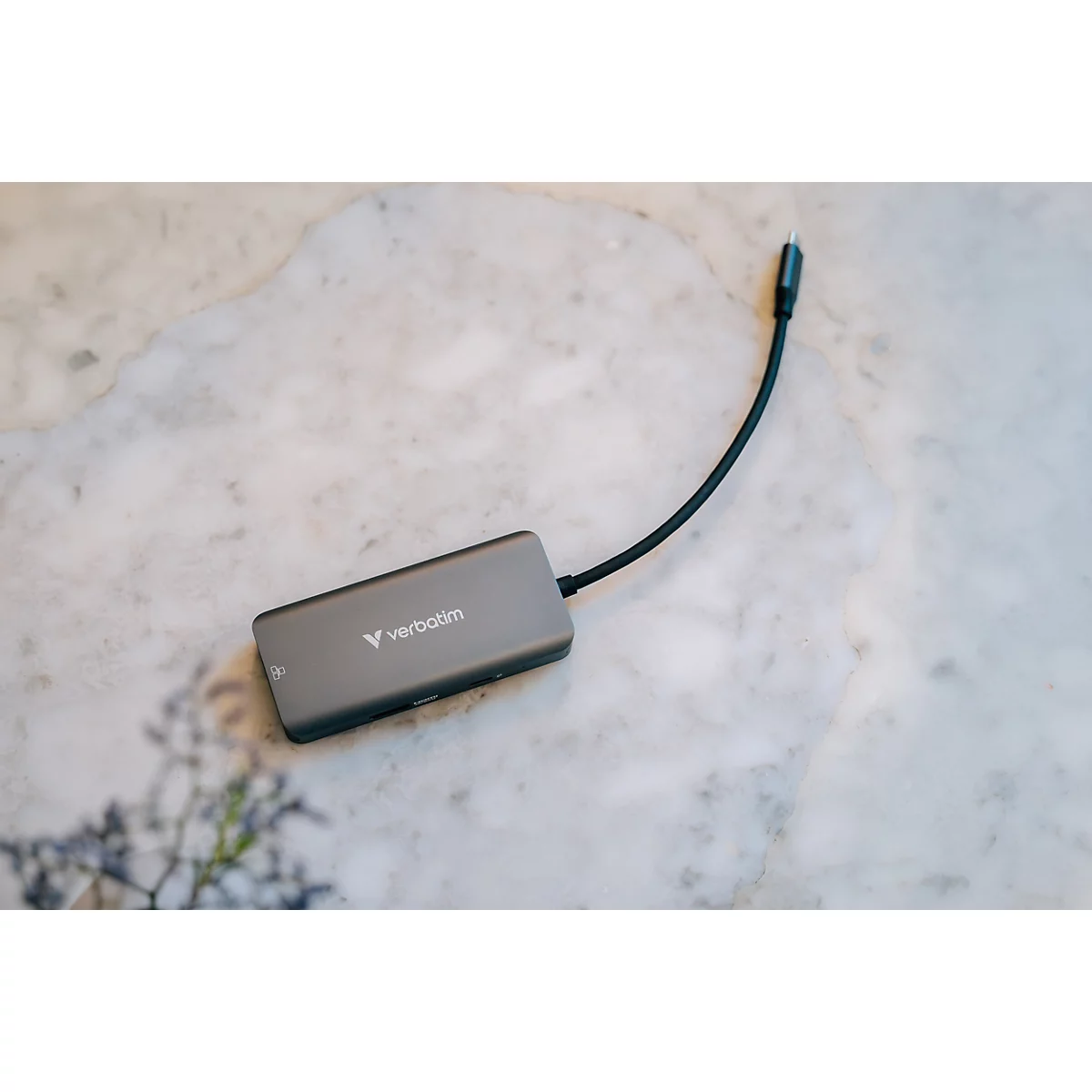 Grauer USB-C-Multiport-Hub der Marke Verbatim auf einem hellen Marmoruntergrund.