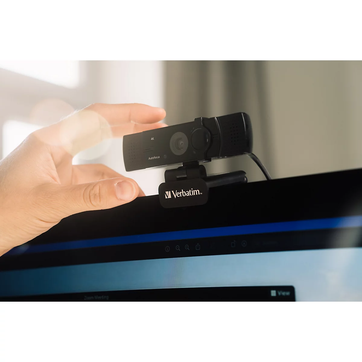 Hand platziert eine schwarze Verbatim Webcam auf einem Monitor.