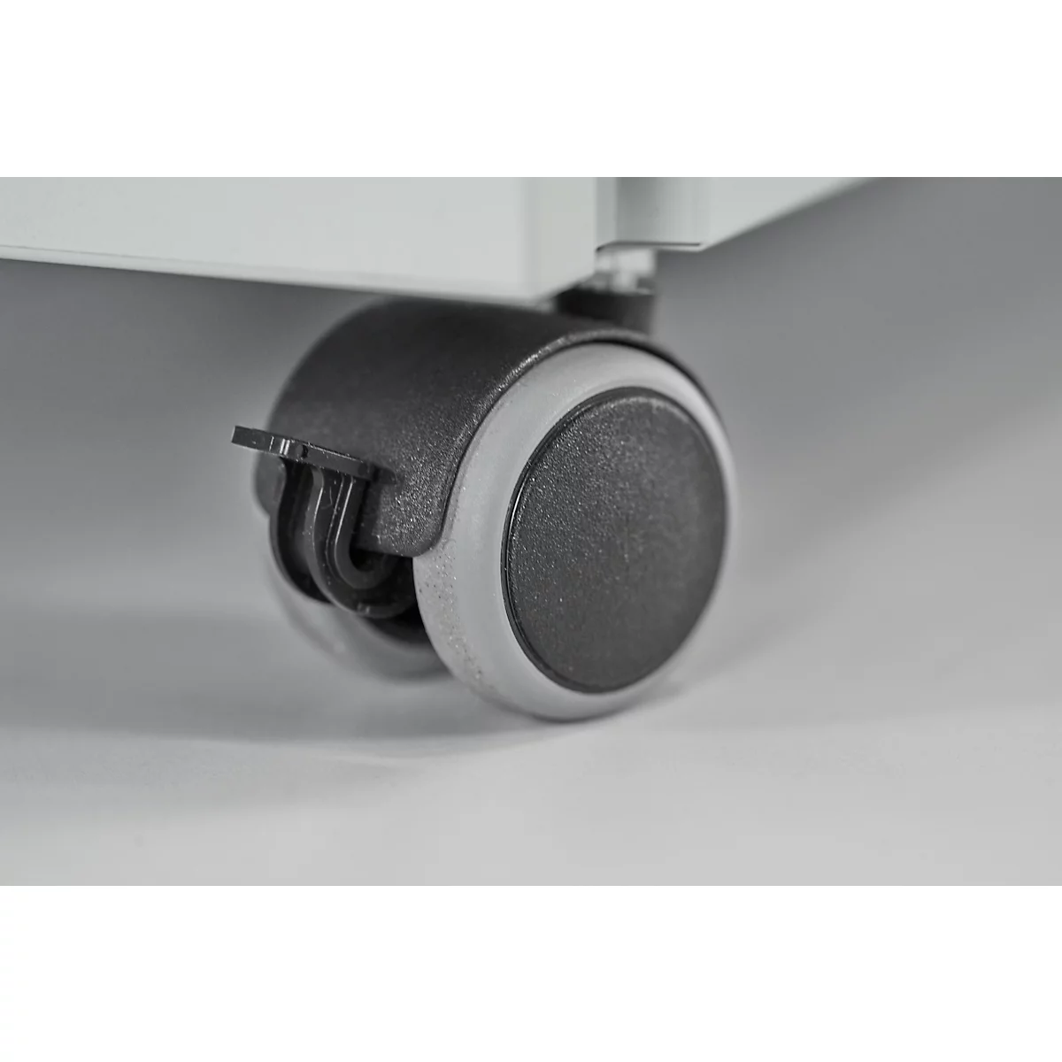 Close-up van een grijs en zwart meubelwiel. Het wiel is bevestigd aan een meubelstuk.