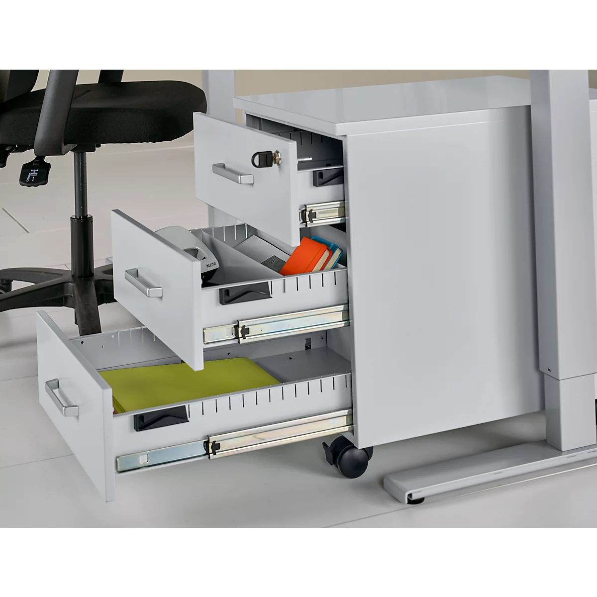 Witte rolcontainer met drie open lades. In één lade een groene plaat, in een andere een oranje boek.