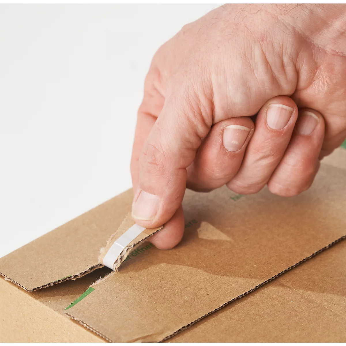 Hand öffnet einen Karton. Die Hand reißt ein Klebeband auf, um den Deckel zu öffnen.