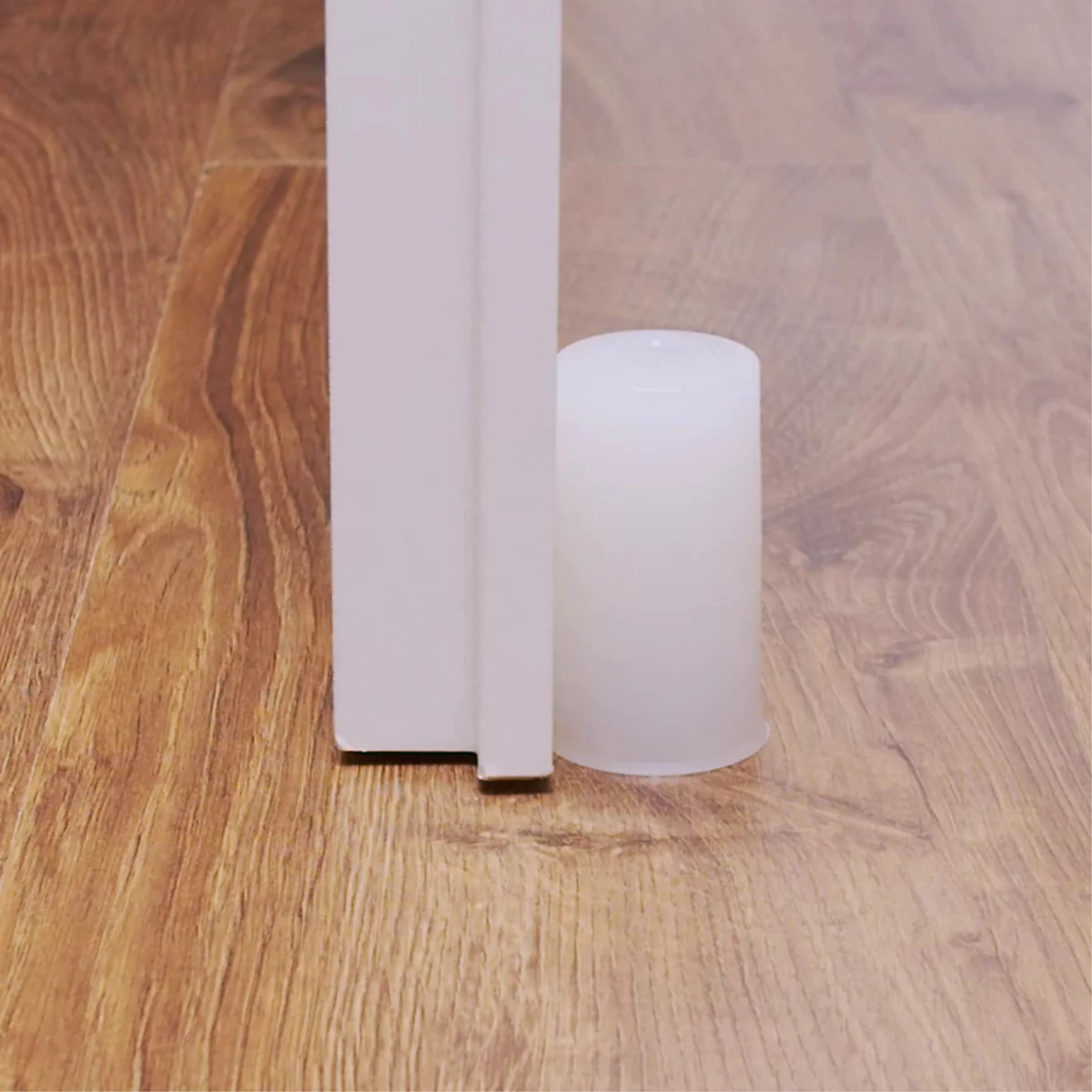 Ein weißer Türstopper hält eine weiße Tür, vor einem Holzboden offen.