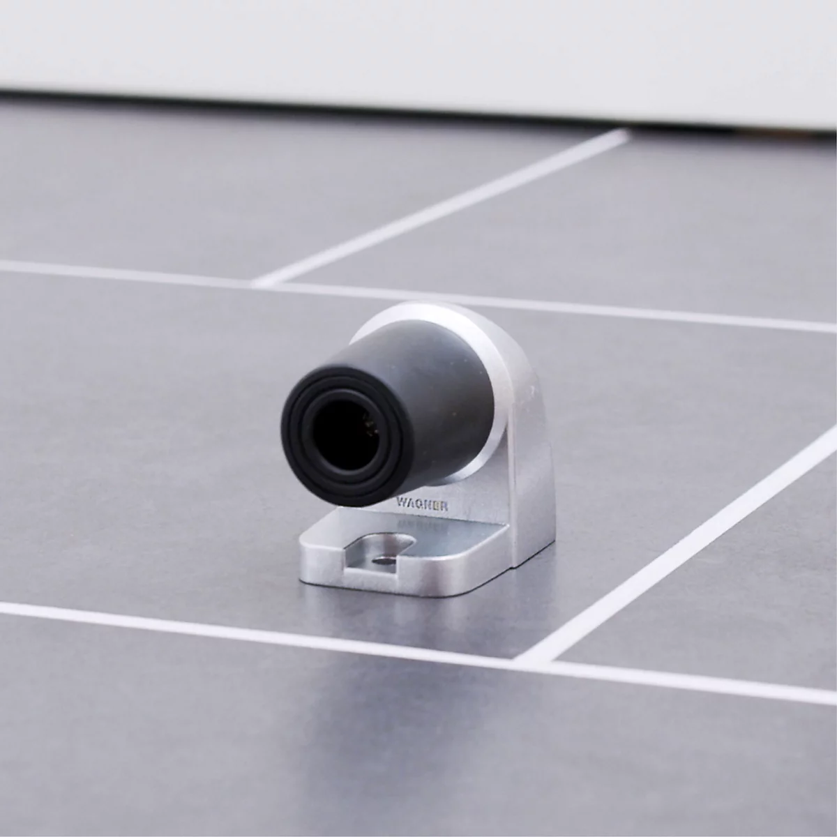 Detailopname van een zwarte camera met een zilveren houder op een grijze ondergrond.