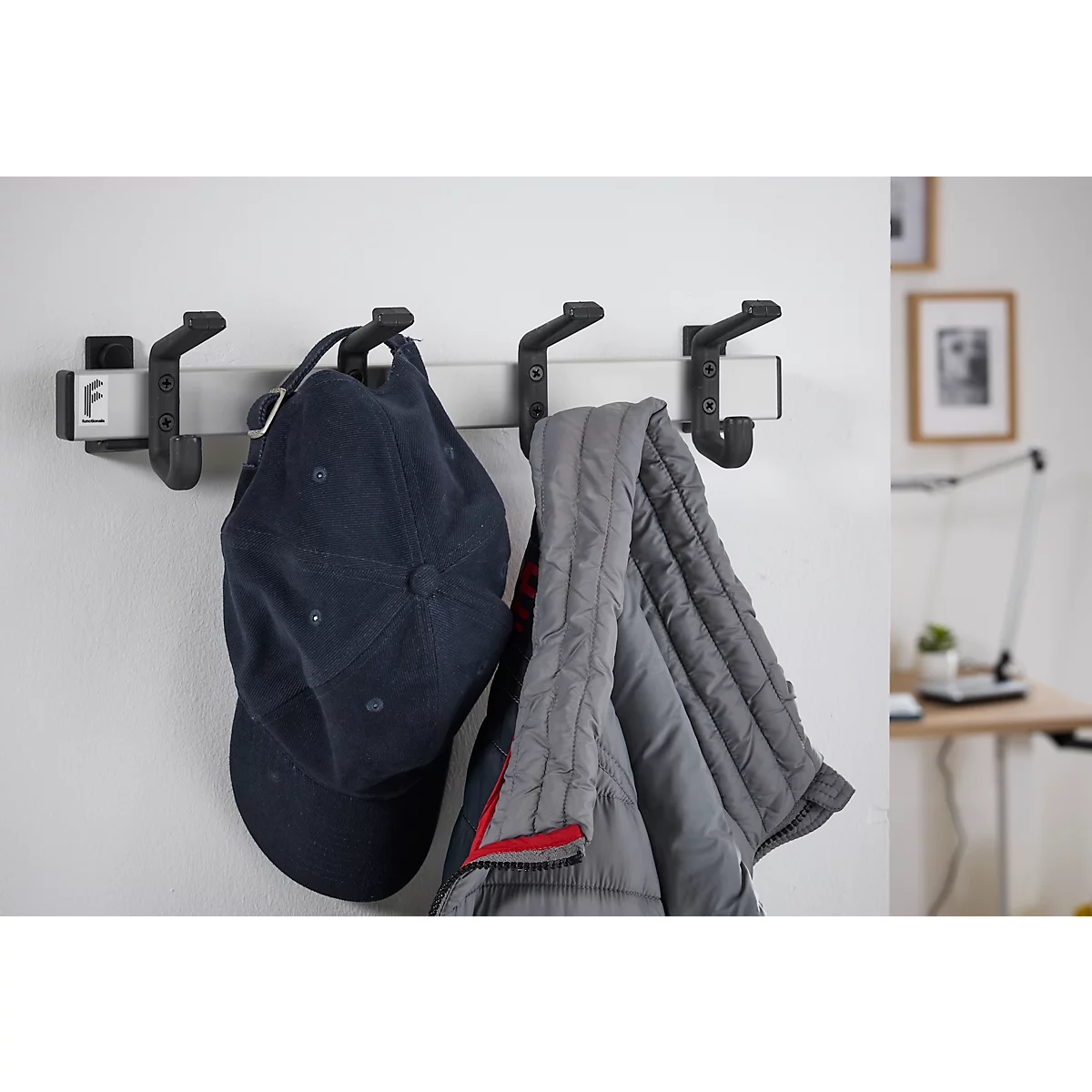 Wall-mounted coat rack with three hooks, holding a cap and a jacket.