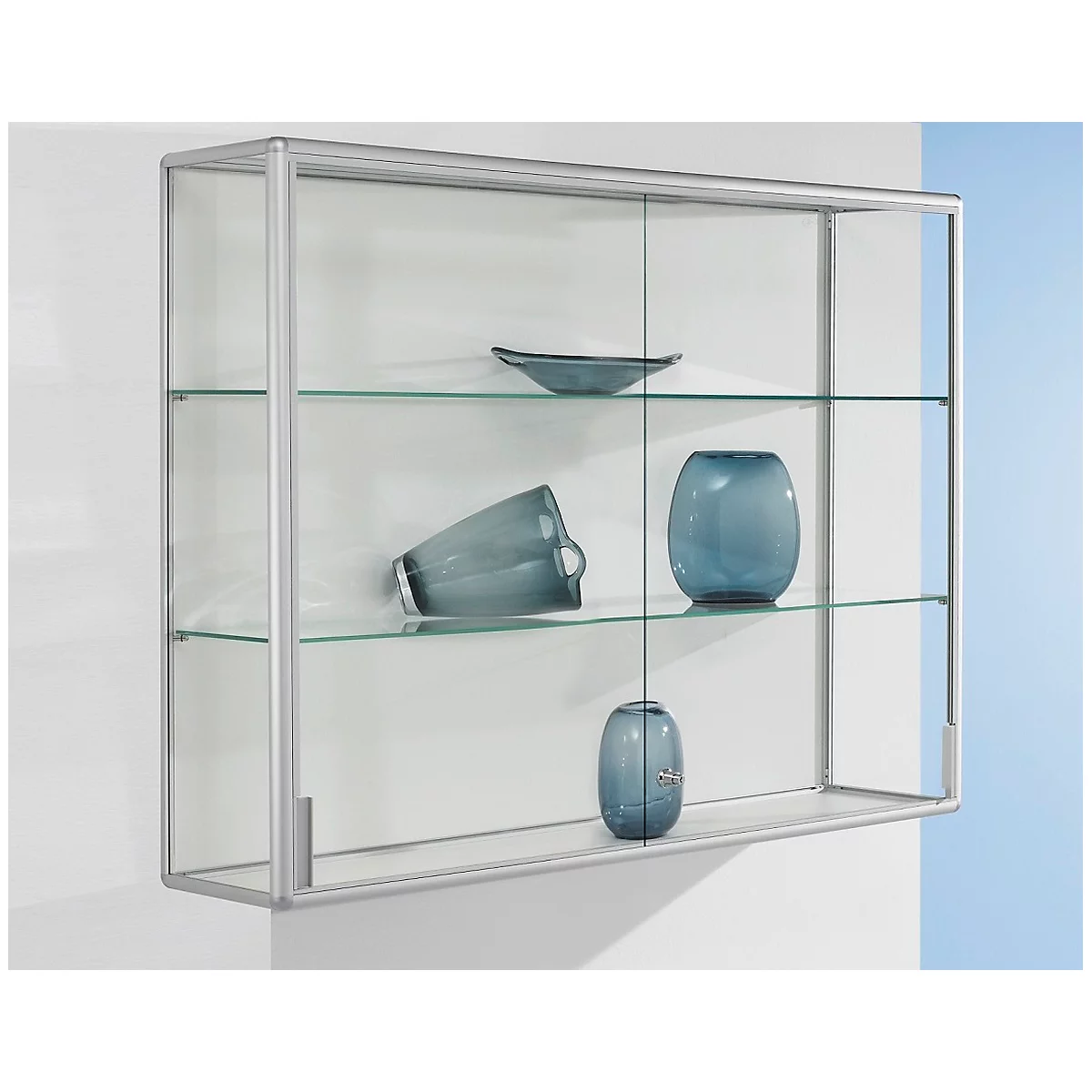 Wall-mounted display cabinet with glass shelves. Blue vases and bowls are on the shelves. The cabinet is attached to a white wall.