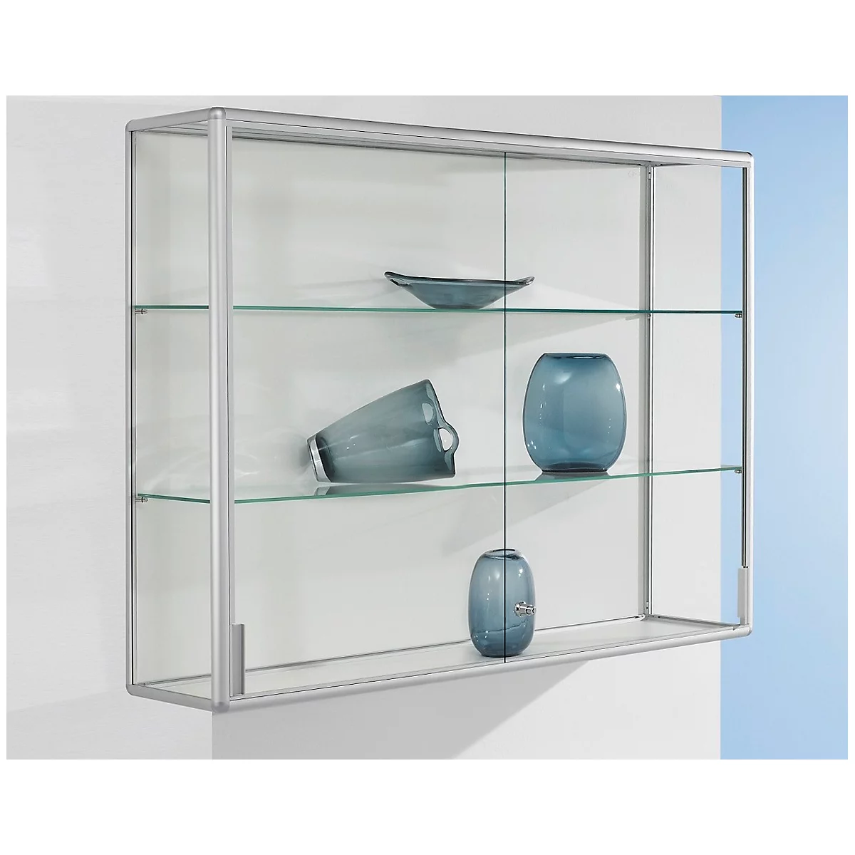 Glass display cabinet on wall. Includes glass shelves and blue glass objects. Silver frame.