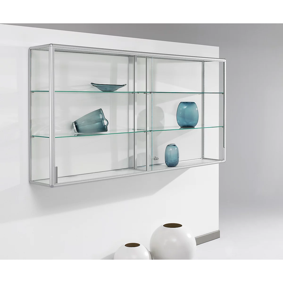 Hanging glass display cabinet with blue decorations, on a wall, with white vases.
