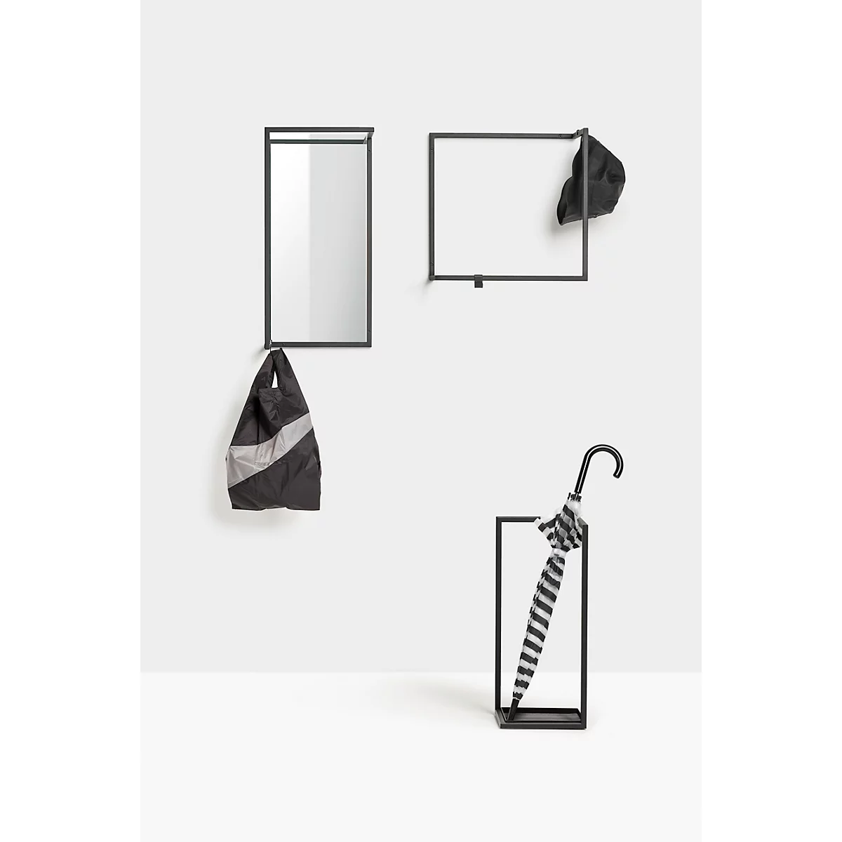 Schwarze Wandgarderobe: Spiegel, Hutablage, Tasche und Regenschirmhalterung mit Regenschirm.