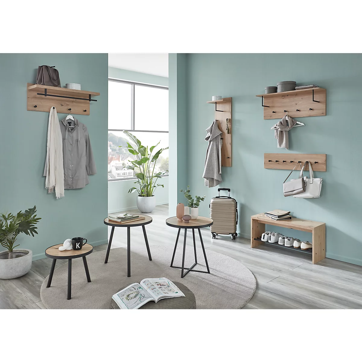 Helles Interieur mit Garderobe, Tischen, Pflanzen und Gepäck. Wandgarderobe aus Holz mit Kleidung. Drei kleine Tische mit schwarzen Beinen. Blumentopf.