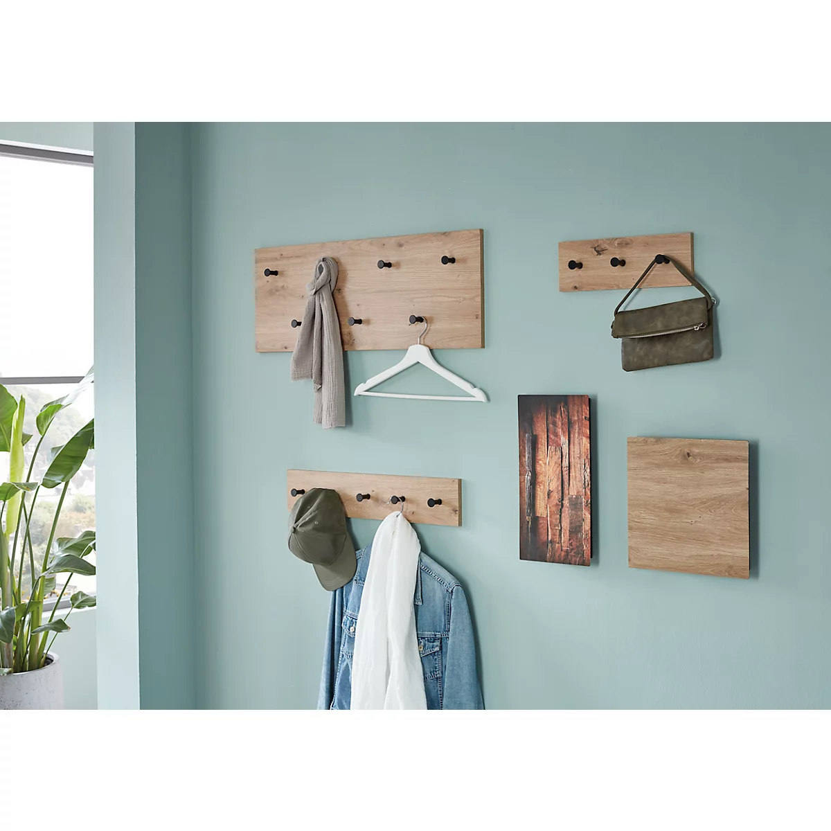 Hölzerne Wandgarderobe mit Kleidung und Accessoires an einer hellblauen Wand.